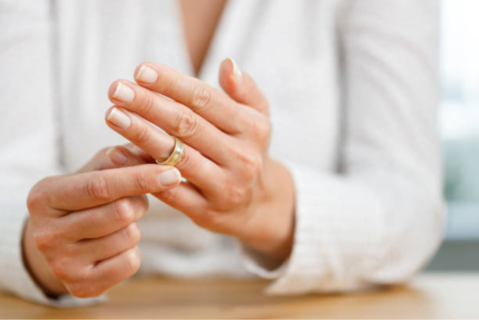 Person measuring their ring size by trying on a gold band, illustrating how to measure your ring size accurately