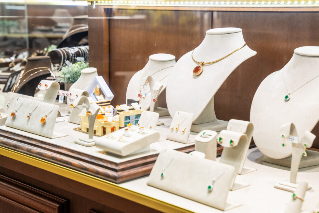 A jewelry display case featuring silver and gold necklaces, rings, and earrings, highlighting different metal choices for personalized jewelry.