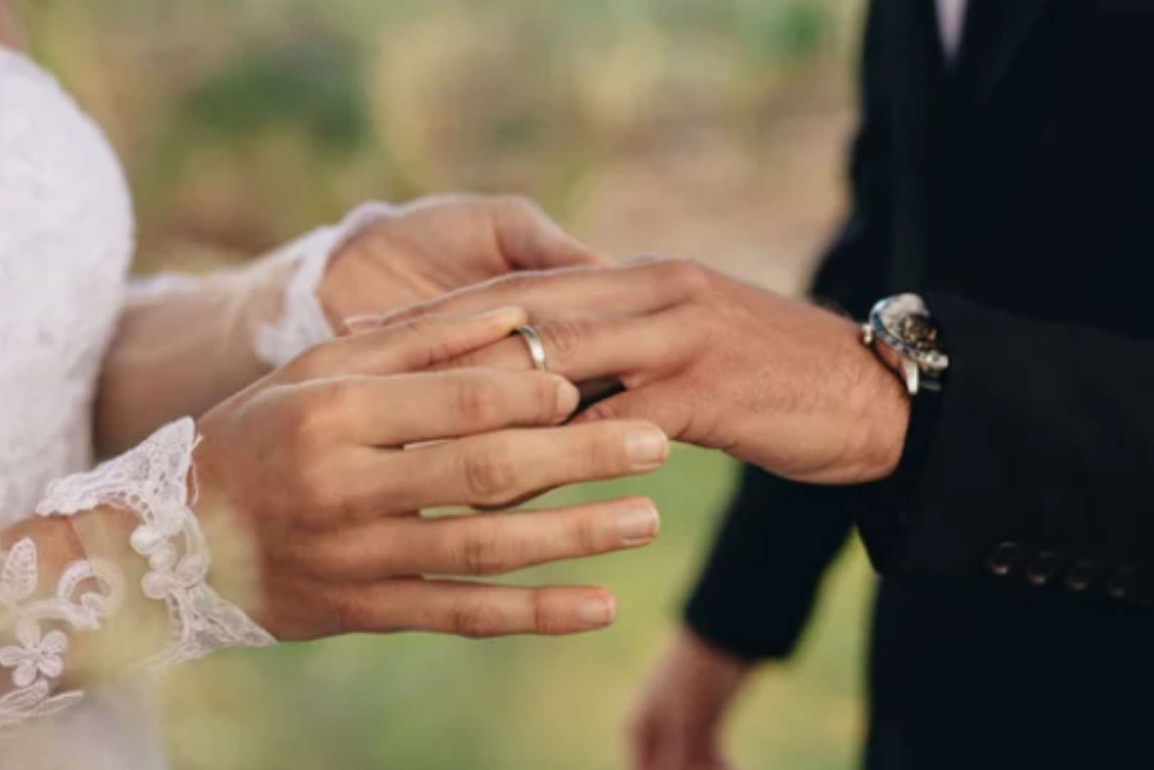 Bride placing a wedding band for men on groom’s hand during ceremony