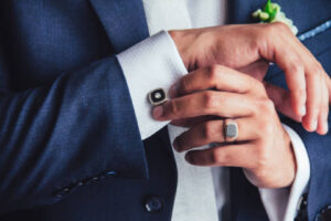 A man in a suit wearing a custom signet ring and cufflinks, two classic Custom Jewelry Ideas for Men for formal style.