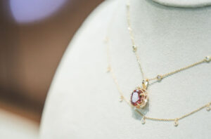 A custom gold necklace featuring an oval-cut pink and red tourmaline pendant, a meaningful Gemstone for Your Zodiac sign.