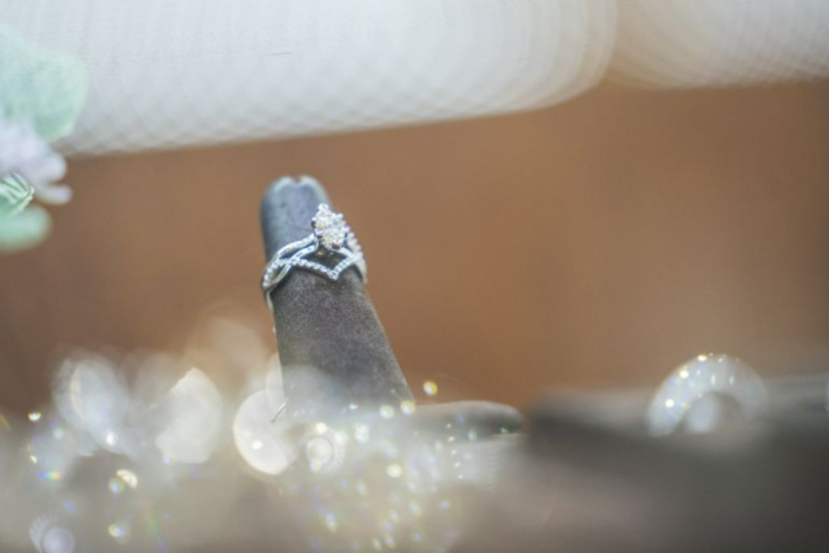 A close-up of a sparkling custom diamond engagement ring with a twisted halo setting, displayed on a jeweler's stand.