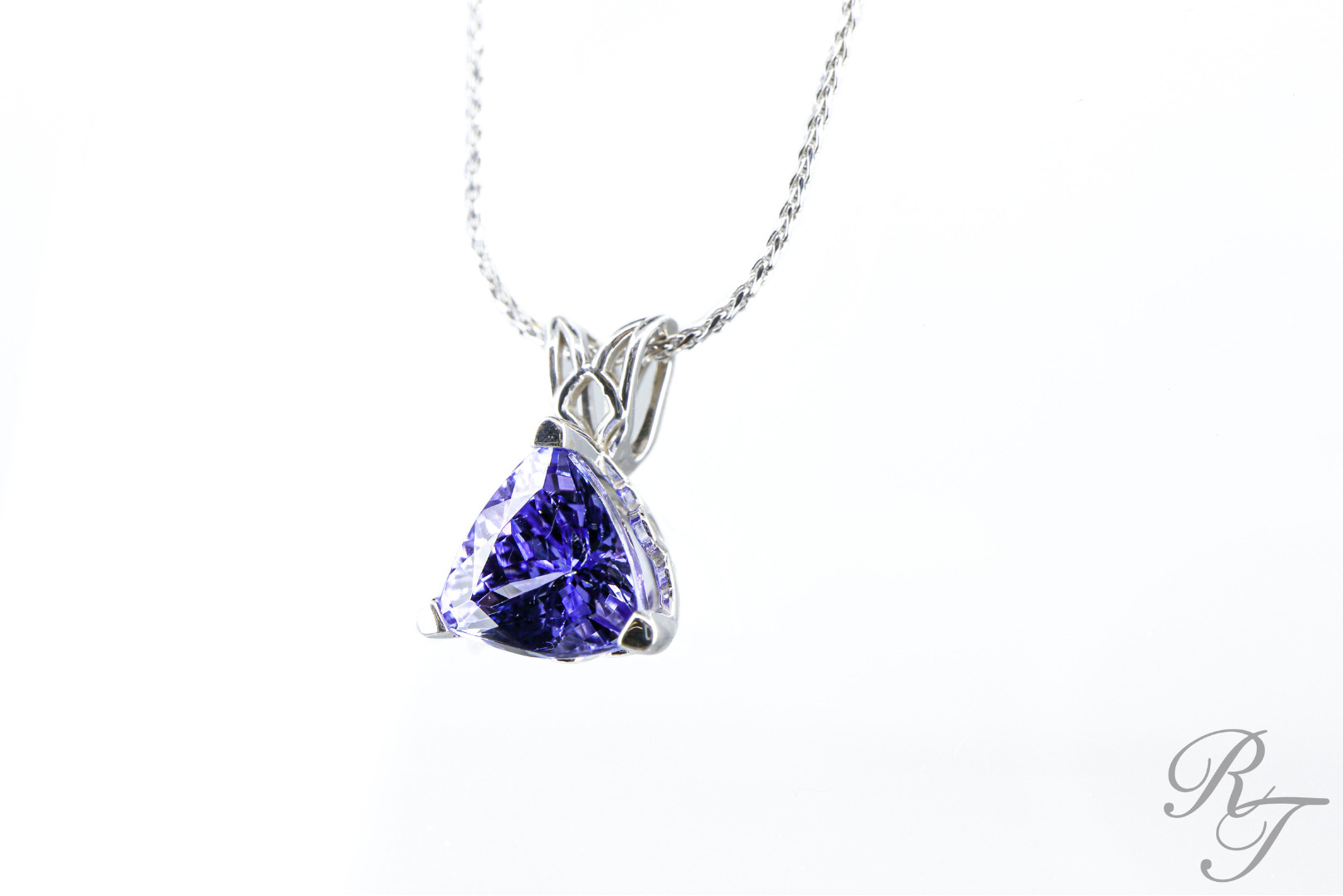 A white gold pendant with a deep violet, trillion-cut Tanzanite gemstone, perfect Jewelry for Christmas gifting.
