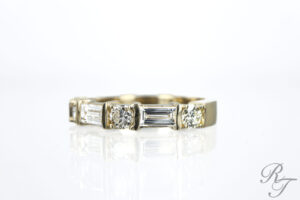 A yellow gold wedding band featuring alternating round brilliant and baguette-cut diamonds from Rick Terry Jewelry Designs.