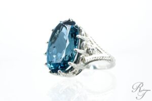 Large oval blue topaz cocktail ring with an intricate multi-prong sterling silver or platinum setting, showcasing secure claw prongs by Rick Terry Jewelry Designs in Knoxville.