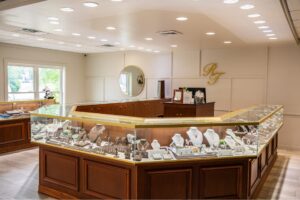Interior view of Rick Terry Jewelry Designs showroom in Knoxville TN, featuring glass jewelry display cases filled with diamond rings, necklaces, and custom jewelry under bright studio lighting.