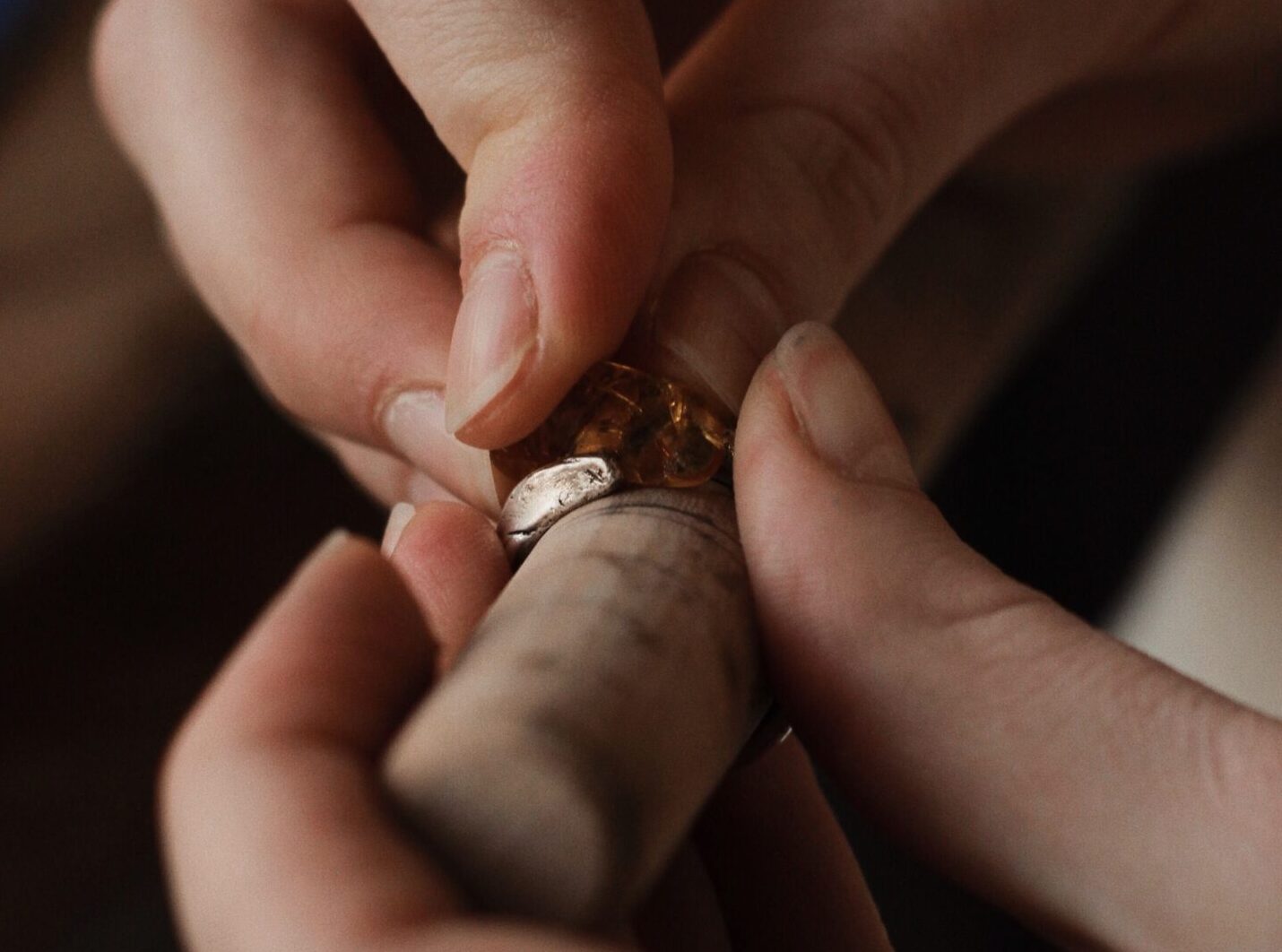 Jeweler hands carefully shaping a handcrafted ring with a gemstone at a jewelry workshop