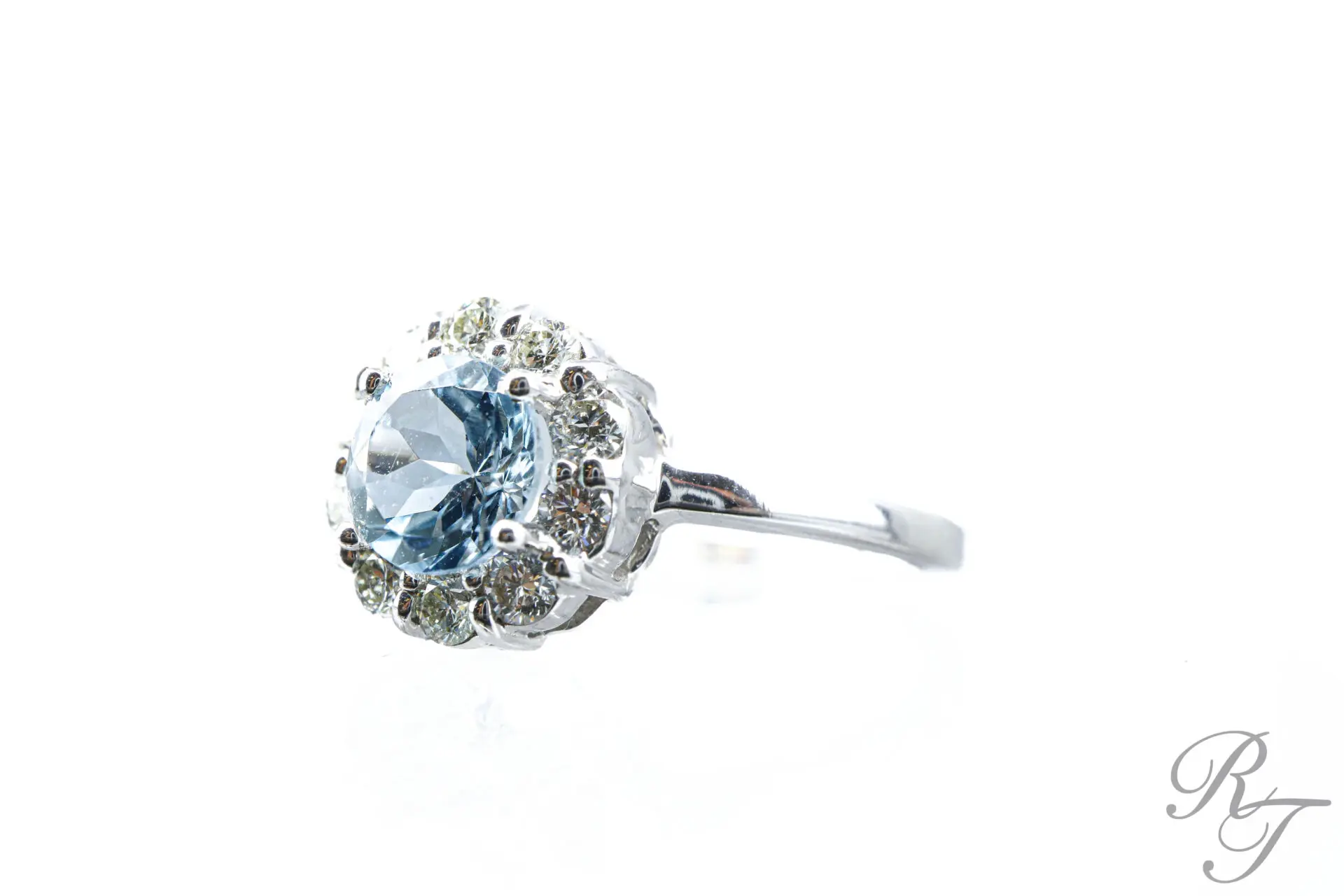 Custom blue gemstone halo ring with diamond surround in white metal handcrafted at Rick Terry Jewelry Designs in Knoxville TN